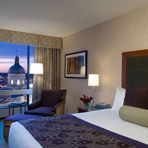 hotel room with clean crisp bed lamp lighting and a large window looking out at the Indiana State Capital Building