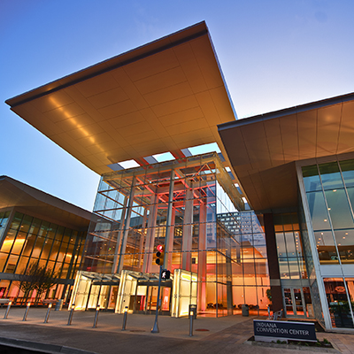 nighttime photo of Indiana Convention Center with climate-controlled walkways and beautiful gold interior lights and modern outdoor directional lights