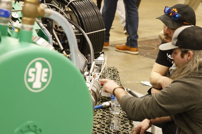 2 men investigating pipe products on the WWETT expo hall floor