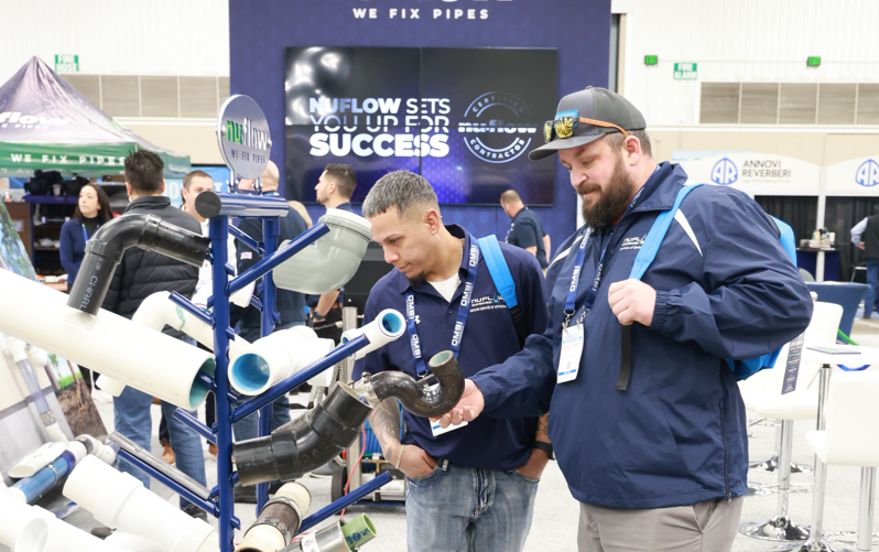 2 men investigating pipe products on the WWETT expo hall floor